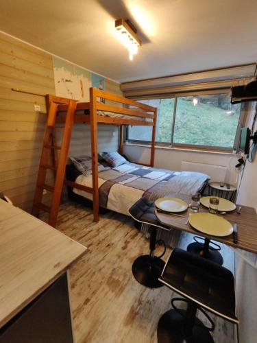 - une chambre avec des lits superposés, un bureau et une table dans l'établissement Studio à Super Besse 800m des pistes, à Besse-et-Saint-Anastaise
