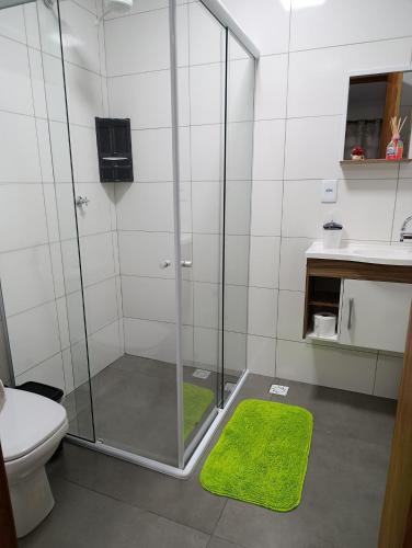 a bathroom with a shower with a toilet and a green rug at Kitnet Sol e Lua in Caparaó Velho