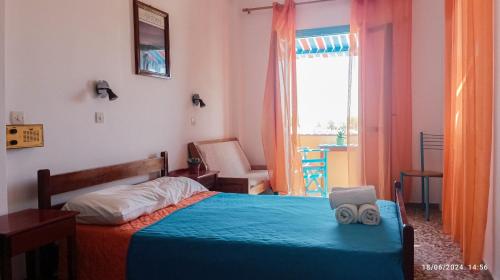 a bedroom with a bed with blue sheets and a window at Chrissi Ammos in Perissa