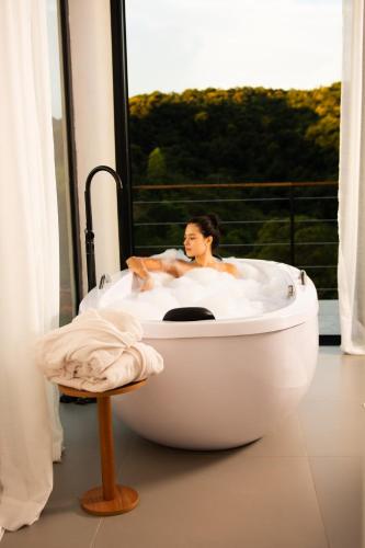 a woman in a bath tub in a room with a window at Chalé Monte Lumier in Tiradentes