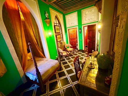 una camera con pareti verdi e tavolo e sedie di Kassr Annoujoum - Luxury Boutique Riad in the Heart of Fès Medina a Fes