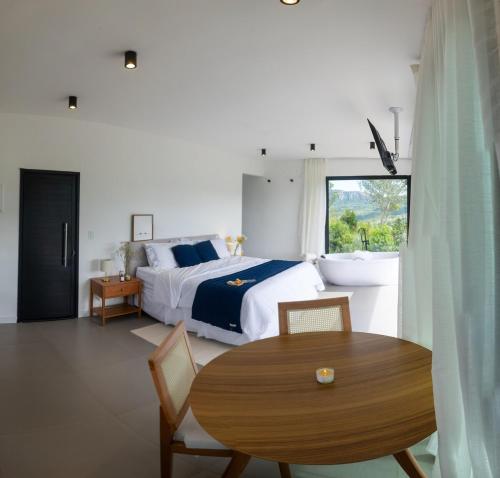 a bedroom with a bed and a table and a window at Chalé Monte Lumier in Tiradentes