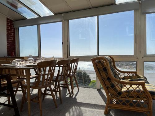 une salle à manger avec une table, des chaises et des fenêtres dans l'établissement La Colombière - Appartement Villa front de mer, à Granville
