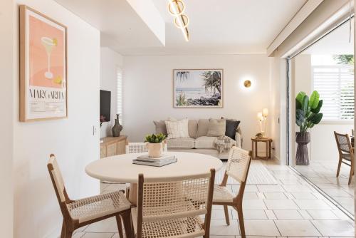 a living room with a table and chairs and a couch at Sleek apartment overlooking pool in Noosa Heads