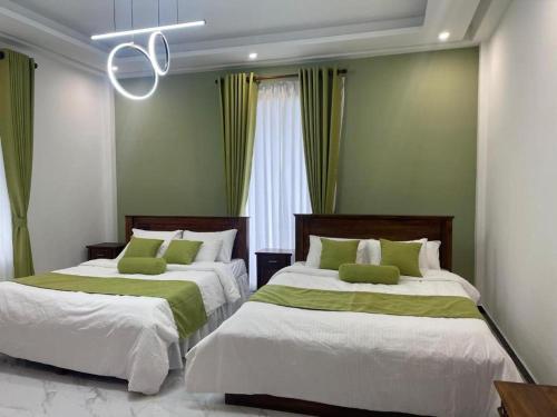 a bedroom with two beds with green walls and a chandelier at DhAJ House in Hatton