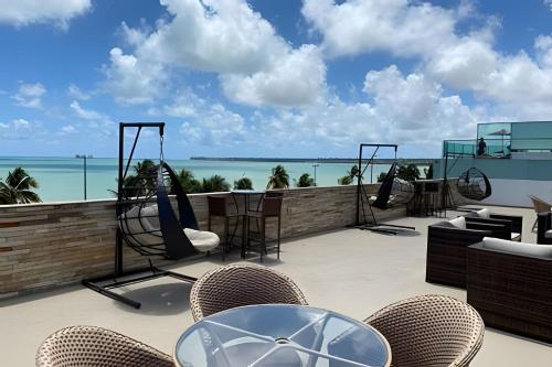 a patio with chairs and a swing and the ocean at Paraíso beira-mar em Tambaú! Nobile Suites #508 in João Pessoa