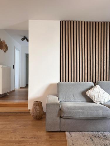 a living room with a gray couch and a wooden floor at Ferienanlage Villa Maare in Gillenfeld