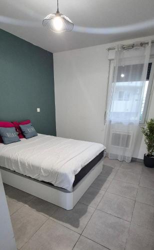 une chambre avec un lit avec des draps blancs et une fenêtre dans l'établissement T2 proche de Montpellier, à Vendargues