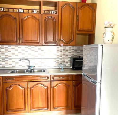a kitchen with wooden cabinets and a sink and a refrigerator at Villa's Daci in Tirana