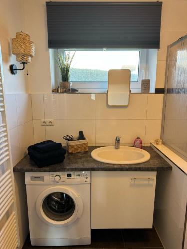 a bathroom with a washing machine and a sink at gemütliche Ferienwohnung Anker in Schilksee am Strand in Kiel