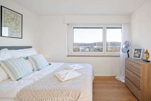 a white bedroom with a bed and a window at STAYY On Top Penthouse-Apartment near Airport in Opfikon