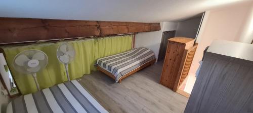 Cette chambre comprend un lit et une fenêtre avec un ventilateur. dans l'établissement Maison de Provence entre mer et montagnes, à Auribeau-sur-Siagne