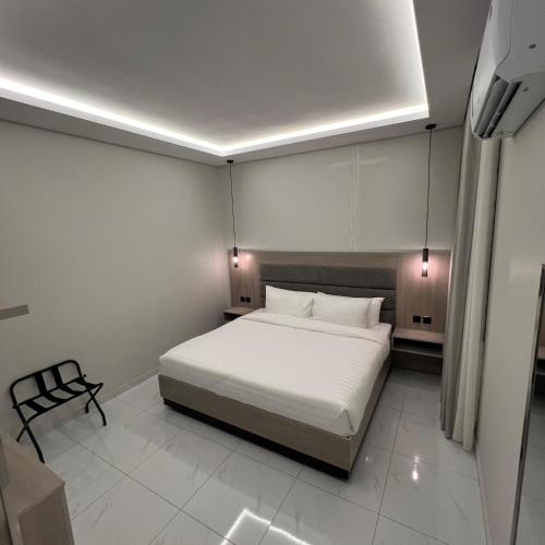 a bedroom with a white bed and a black chair at Bee House in Taif