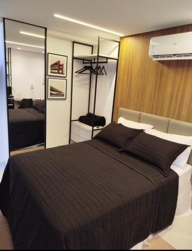 a bedroom with a large black bed and a mirror at Breeze flat in João Pessoa