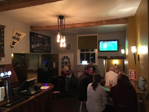 a group of people sitting in a bar with a man playing guitar at The Swan Taphouse in Ironbridge