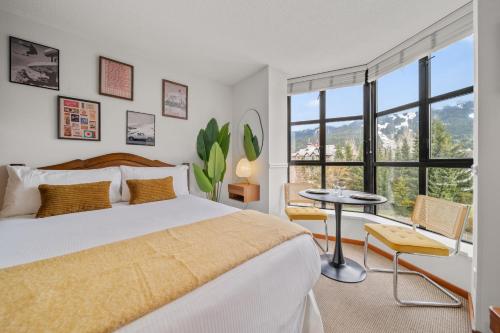 a bedroom with a large bed and a table and chairs at Mid Century Modern - Studio w Pool & Hot Tub in Whistler