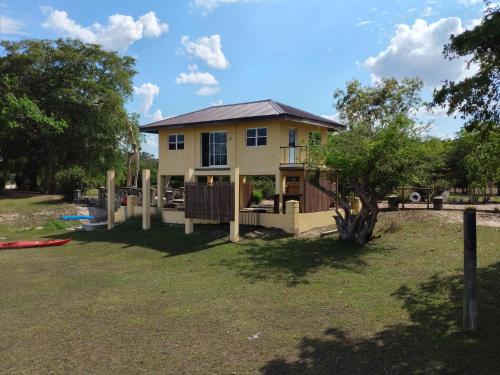 a house with a fence in front of a yard at CROOКED TREE LODGE Belize in Crooked Tree