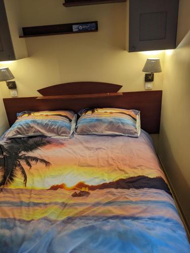 une chambre avec un lit avec un tableau dessus dans l'établissement Mobil-home, à Arconcey