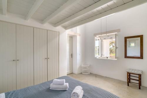a white bedroom with a bed and a mirror at A summer house a few steps from the beach in Santa Maria