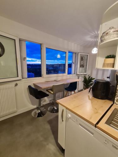 une cuisine avec une table, des chaises et des fenêtres dans l'établissement Appartement entier proche du Parc de la Tête d 'Or, à Villeurbanne