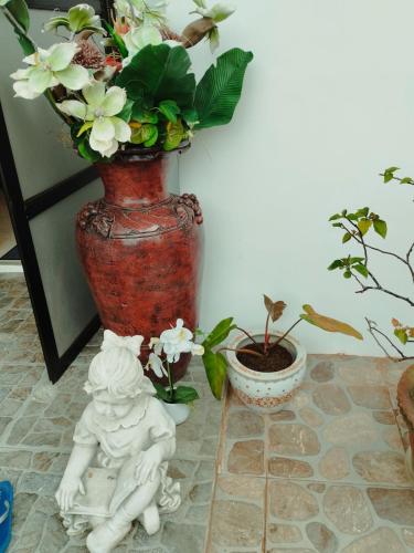 a vase with flowers in it next to two plants at LR Bungalow in Tacloban
