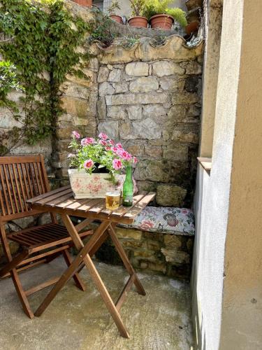 a wooden table with flowers on it next to a stone wall at House in Rural Sardinia in Collinas