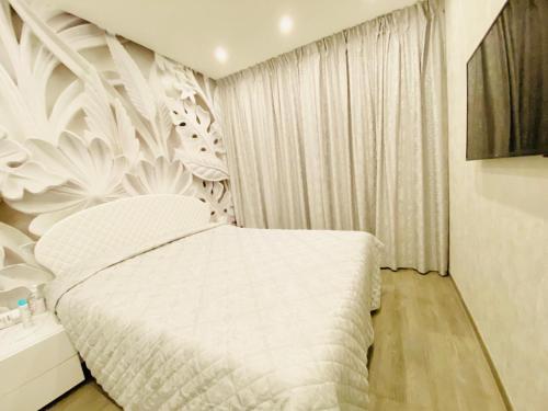 a bedroom with a white bed with a floral wall at Hope House in Villasimius