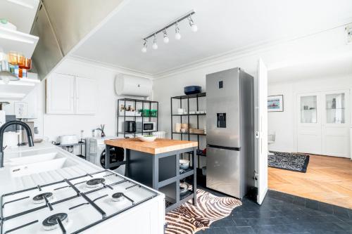  La cuisine est équipée de placards blancs et d'un réfrigérateur. dans l'établissement Elégance Vendôme & Tuileries, à Paris