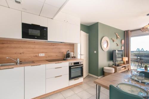 une cuisine avec des placards blancs et une table avec une salle à manger dans l'établissement Atlantic Selection - Vagues en Vue, à l'Estacade avec piscine, à Capbreton