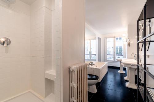 La salle de bains blanche est pourvue de 2 lavabos et d'une baignoire. dans l'établissement Elégance Vendôme & Tuileries, à Paris