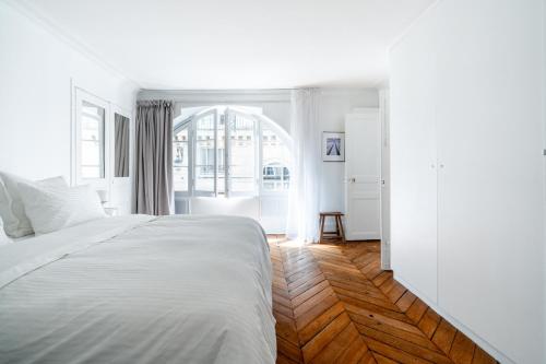 une chambre avec un lit blanc et un parquet dans l'établissement Elégance Vendôme & Tuileries, à Paris