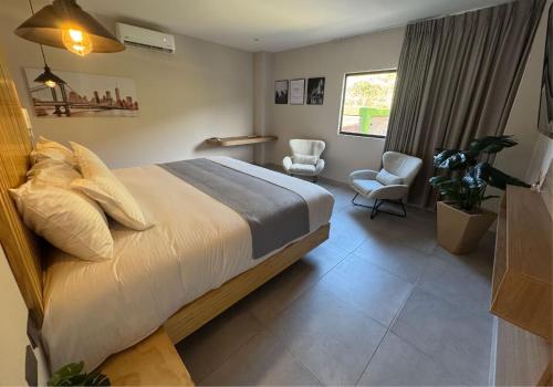 a bedroom with a bed and two chairs and a window at Hotel San Gil House in San Gil