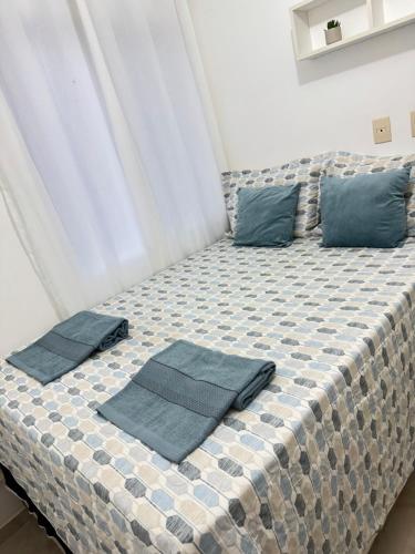 a bed with blue pillows on top of it at Apto completo com ar, piscina 2 quartos in Camaçari