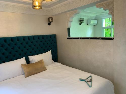 a bedroom with a bed with a blue headboard and a mirror at RIAD Jad in Fès