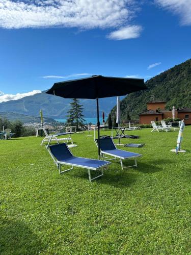 a group of lounge chairs sitting in a field with an umbrella at BonBon Dom Lake View in Varone