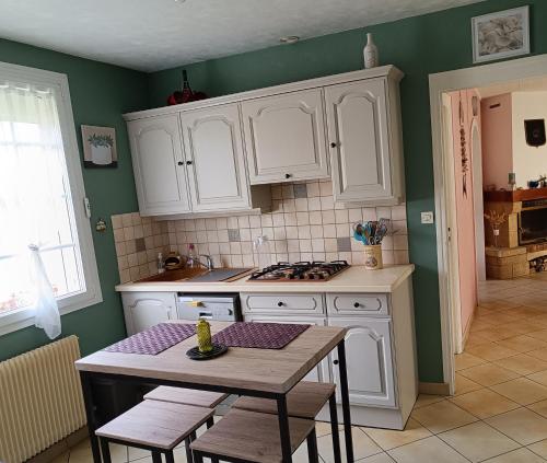 a kitchen with white cabinets and a table with chairs at Cottage le petit Tôt in Barneville-Carteret
