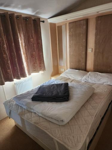 a bed with a black pillow on top of it at Summerlands, Ingoldmells 8 berth caravan in Skegness