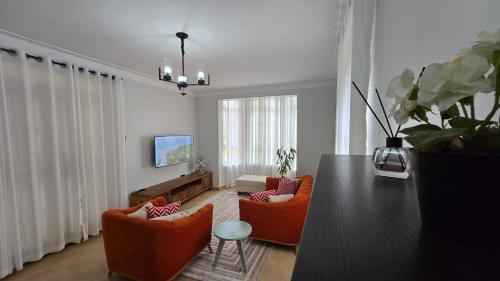 a living room with orange chairs and a table at Tranquility Homes Muyenga in Kampala