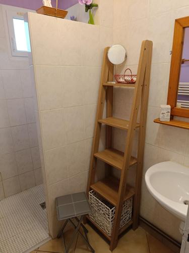 - une étagère en bois dans la salle de bains pourvue d'un lavabo dans l'établissement Cottage le petit Tôt, à Barneville-Carteret