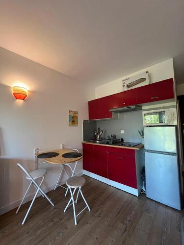 une cuisine avec des armoires rouges et une table et des chaises dans l'établissement At Anne-Laure and Martine's, à Argelès-sur-Mer