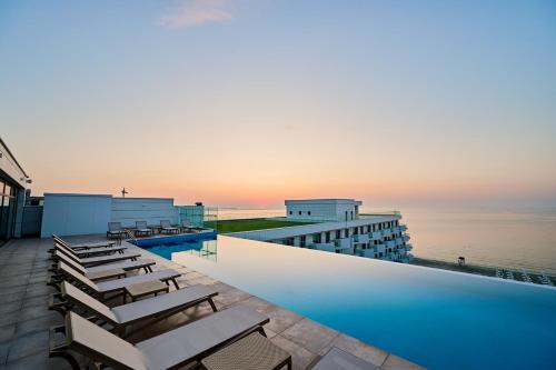 a hotel swimming pool with chairs and the ocean at Exotic Sunrise View in Infinity Pool & Spa Resort in Mamaia Sat/Năvodari