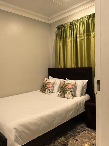 a bed with two pillows and a green curtain at Your Perfect Escape with Breathtaking Lake Views in Pretoria
