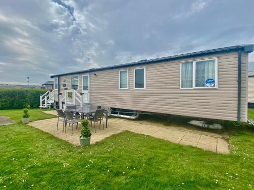 a mobile home with a table and chairs in a yard at Caravan Church farm holiday village in Pagham