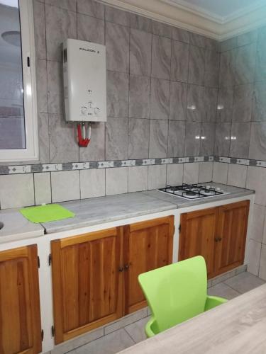 a kitchen with a stove and a green chair at Appartement Jasmin Tabarka in Tabarka