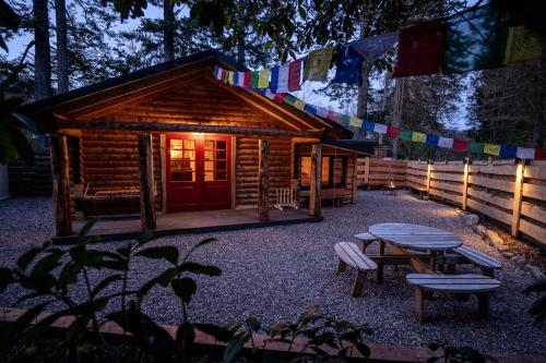 a log cabin with a table and benches and flags at The Happy Cabin Woodland Hideaway by the River in Banavie