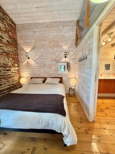 une chambre avec un grand lit dans un mur de briques dans l'établissement Le Duplex de l'Artisterie, à Mondonville