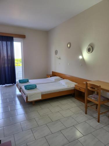 a bedroom with a bed and a desk and a window at Pyrgos Hotel Apartments in Kremasti