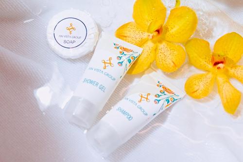 a bottle of sunscreen next to two yellow flowers at An Vista Hotel in Nha Trang