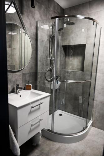 a bathroom with a shower and a sink and a glass shower at Apartament Podmiejska in Kalisz