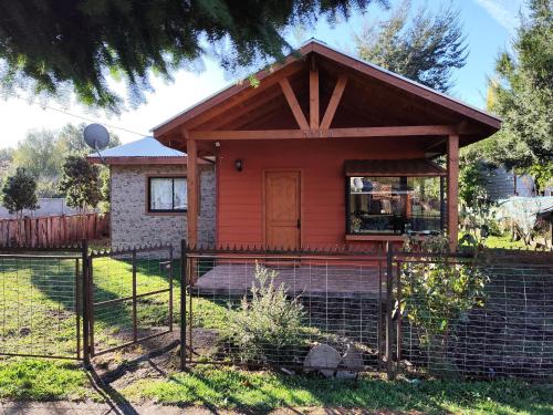 a small red house with a porch at Cabaña camino Conguillio Sector Urbano in Melipeuco